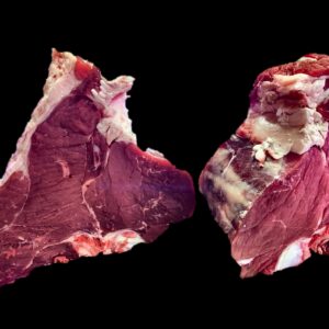Due bistecche alla fiorentina su fondo nero, tagliate alte: si vedono l&rsquo;osso, il magro e il bordo di grasso