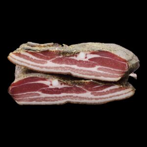 Pancetta stagionata tagliata a metà su fondo nero: le venature di magro e di grasso e la crosta di pepe