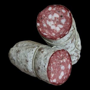 Due salami toscani su fondo nero, uno tagliato: grana rossa, lardelli bianchi e grani di pepe